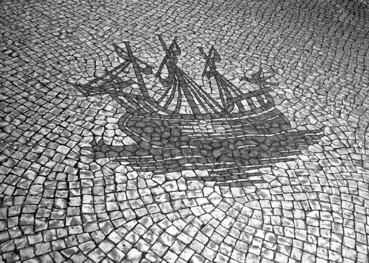 Fotografia de uma calçada típica Portuguesa com uma caravela portuguesa